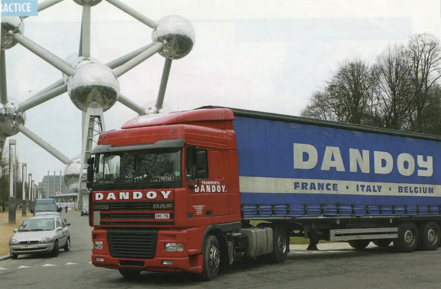 Camion rouge de la société Dandoy devant l'Atomium à Bruxelles, remorque bleue avec inscriptions France, Italie, Belgique.